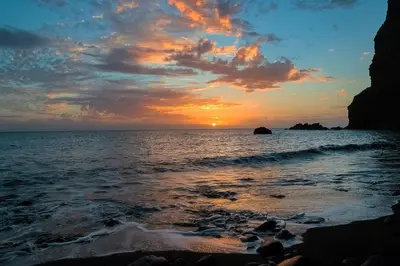 a sunset over the ocean with a rocky beach at Madalena Sunset by Homie in Madalena do Mar