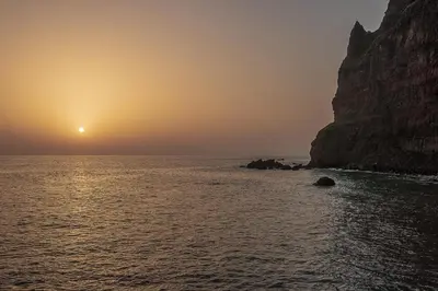 a sunset over the ocean near a rocky cliff at Madalena Sunset by Homie in Madalena do Mar