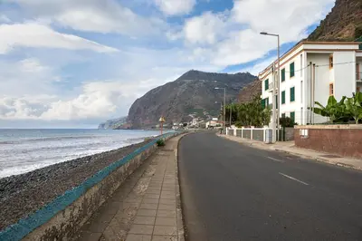 a street next to the ocean with a mountain at Madalena Sunset by Homie in Madalena do Mar