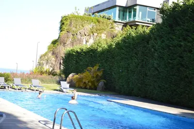 two people in a swimming pool with a house in the background at Peaceful Apartment in Funchal
