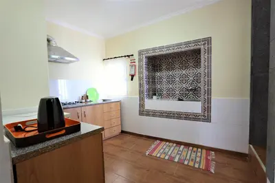 a room with a kitchen with a tv on a wall at Casa do Seixal in Seixal