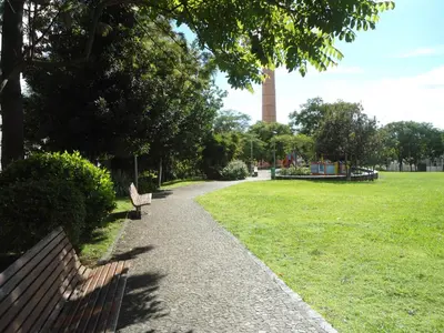 a park with two benches and a tower in the distance at Panoramic View Apartment in Funchal