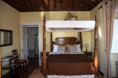 a bedroom with a wooden canopy bed with pillows at Vila Afonso in Estreito de Câmara de Lobos