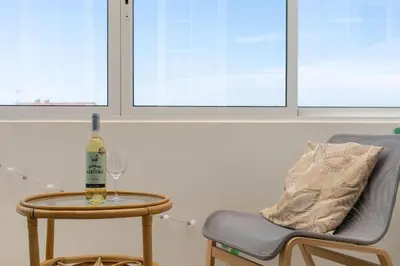a bottle of wine on a table next to a chair at Sweet Home Sagres in Sagres