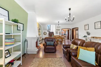 a living room with leather furniture and a dining room at Sweet Home Sagres in Sagres