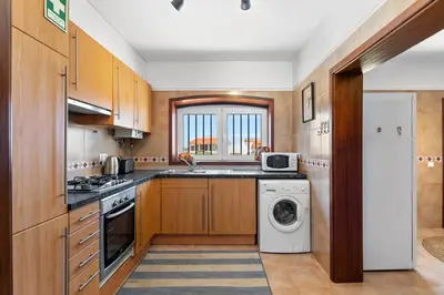 a kitchen with wooden cabinets and a washer and dryer at Sweet Home Sagres in Sagres