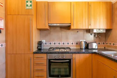 a kitchen with wooden cabinets and a stove top oven at Sweet Home Sagres in Sagres