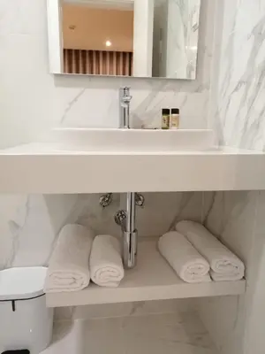 a white bathroom with a sink and towels on a shelf at Monumental Plaza by Petit Hotels in Funchal