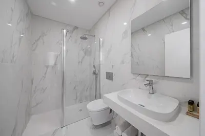 a white bathroom with a sink and a shower at Monumental Plaza by Petit Hotels in Funchal