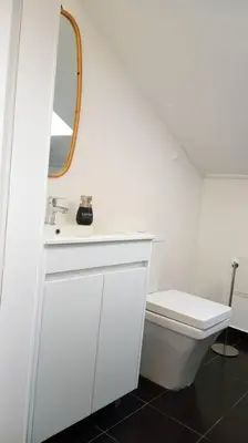 a white bathroom with a toilet and a mirror at Lazy Lizard Studio in Seixal