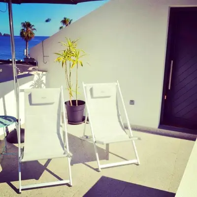 two white chairs sitting on a porch next to a door at Lazy Lizard Studio in Seixal