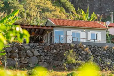 a small house behind a stone wall at Casa da Rocha de Baixo by An Island Apart in Santana