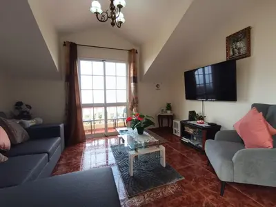 a living room with a couch and a television at Charm Penthouse Ocean View in Calheta