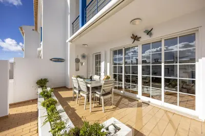 a table with a bottle of wine and a glass at CoolHouses Luz, Lovely 3 Bed Townhouse & sea views, Casa Baía da Vida in Luz