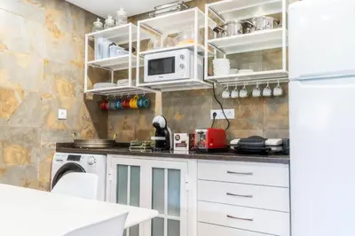 a kitchen with white cabinets and a white refrigerator at Madeira Bird House - House in the Mountains With Garden in São Vicente