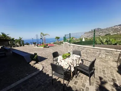 a table and chairs with the ocean in the background at Villa Nova Madeira in Funchal Casa A and B in Funchal