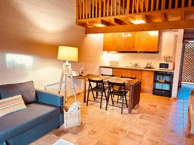 a living room with a couch and a table and a kitchen at Casinha da Praia in Carrapateira
