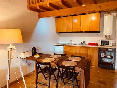 a kitchen with a wooden table with chairs and a counter at Casinha da Praia in Carrapateira