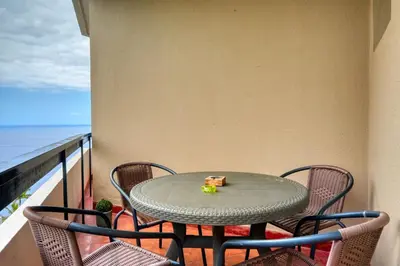 a table and chairs on a balcony with the ocean at Blue View, a Home in Madeira in Funchal