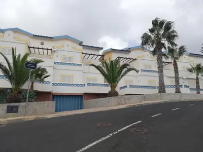a building with palm trees in front of a street at Apartamento Pedras Pretas in Porto Santo