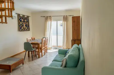 a living room with a green couch and a table at Apartamento Pedras Pretas in Porto Santo