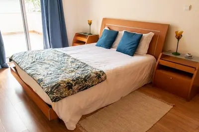 a bedroom with a large bed with blue pillows at Apartamento Pedras Pretas in Porto Santo
