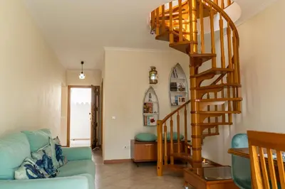 a spiral staircase in a living room with a blue couch at Apartamento Pedras Pretas in Porto Santo