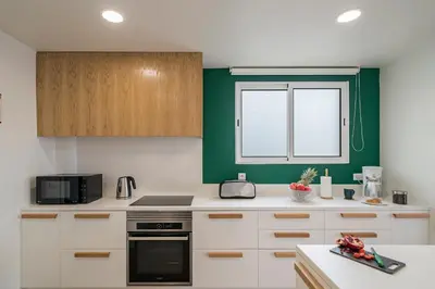 a kitchen with white cabinets and a green wall at Lido I by An Island Apart in Funchal