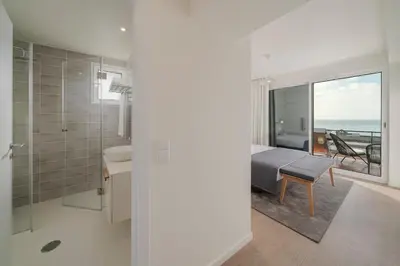 a white bathroom with a bed and a view of the ocean at Lido I by An Island Apart in Funchal