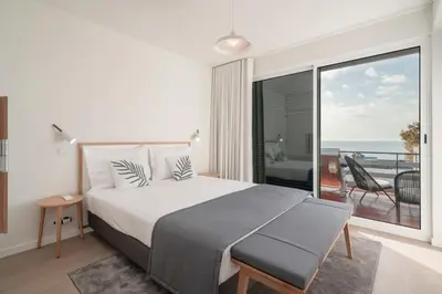 a bedroom with a large bed and a balcony at Lido I by An Island Apart in Funchal