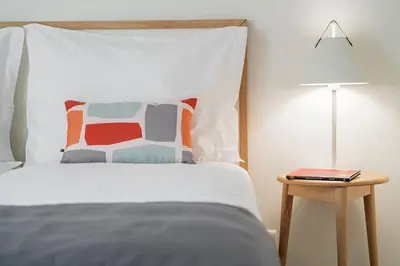 a bed with a pillow and a table with a lamp at Lido I by An Island Apart in Funchal