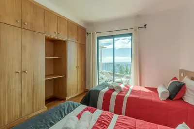 a bedroom with two beds and a large window at Ocean View Tabua by Holiday Rental Madeira in Ribeira Brava