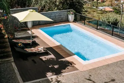 a swimming pool with an umbrella and chairs and an umbrella at La Madérene with Pool by Stay Madeira Island in Tábua