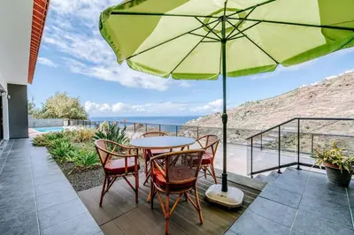 a patio with a table and chairs and an umbrella at La Madérene with Pool by Stay Madeira Island in Tábua