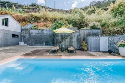 a swimming pool with an umbrella and chairs next to a fence at La Madérene with Pool by Stay Madeira Island in Tábua