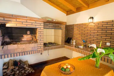 a kitchen with a fireplace and a table with a bowl of fruit at Casa da Caixeira in Arco da Calheta