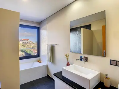 a bathroom with a sink and a tub and a mirror at Villa Serramar in Estreito da Calheta