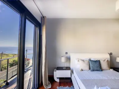 a bedroom with a bed and a large window at Villa Serramar in Estreito da Calheta