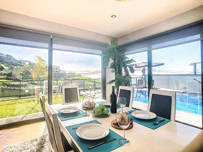 a dining room with a table and a large window at Villa Serramar in Estreito da Calheta