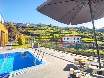 a patio with an umbrella and a swimming pool at Villa Serramar in Estreito da Calheta