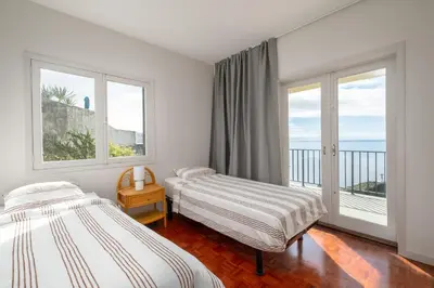 two beds in a room with a balcony at Garajau House - Sunrise to Sunset Ocean View Villa in Caniço