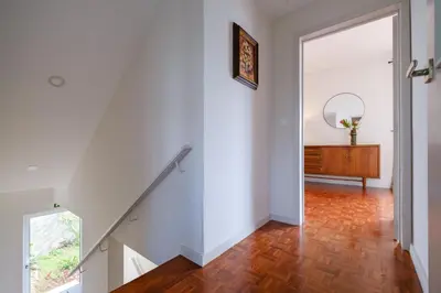 a white hallway with a staircase and a mirror at Garajau House - Sunrise to Sunset Ocean View Villa in Caniço