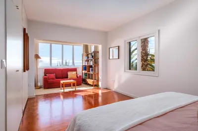 a white room with a bed and a red couch at Garajau House - Sunrise to Sunset Ocean View Villa in Caniço