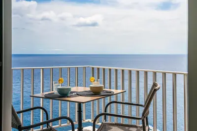 a table and chairs on a balcony with the ocean at Funchal Sea View I by An Island Apart in Funchal
