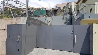 a fence with two doors in front of a building at Casa Atlantico Suite in Ribeira Brava
