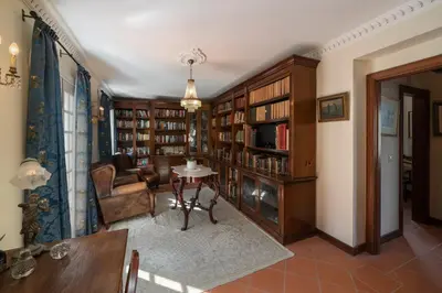 a living room with a chair and a table and bookshelves at Casa Das Videiras in Seixal