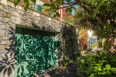 a green garage door on a stone building at Casa Das Videiras in Seixal