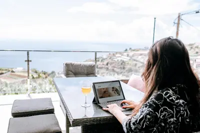 a woman sitting at a table with a laptop at Casa das Voltinhas in Ponta do Sol