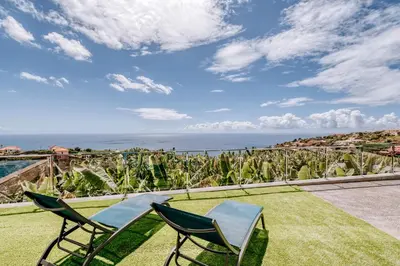 two chairs on a lawn with the ocean in the background at Casa das Voltinhas in Ponta do Sol