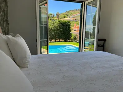 a bedroom with a bed and a view of a pool at Casa Roc Madeira - 5 Bedrooms - Ocean and City Views - Private Heated Pool in Funchal